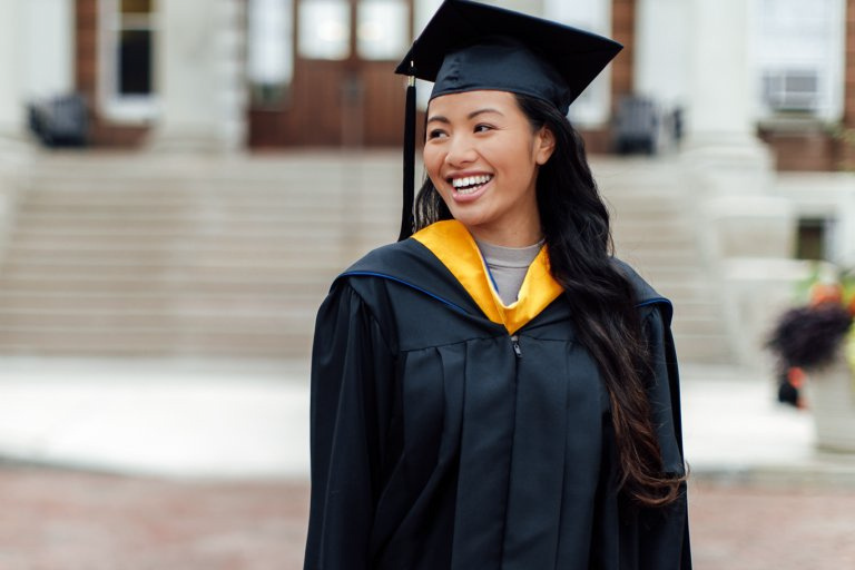 Young woman smiling, wearing a graduation gown